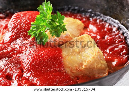 codfish fillet with tomato sauce in a iron pan
