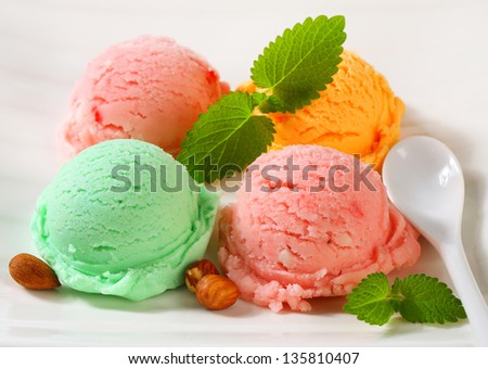 four ice cream scoops with different flavors, decorated with mint and almonds