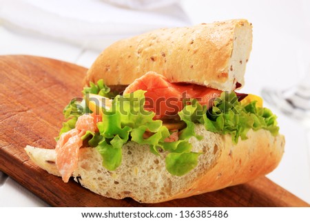 salmon sandwich with lettuce on a wooden cutting board