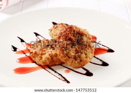 three fried burgers decorated with sauce on a plate