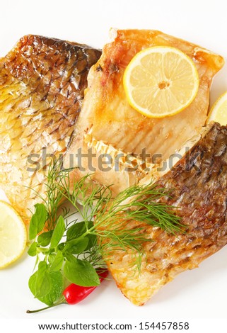 carp fillet with skin served with lemon, chili pepper and dill