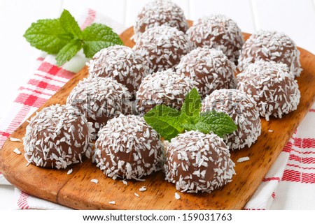 thirteen dark chocolate pralines breaded in a grated coconut, served on a wooden cutting board