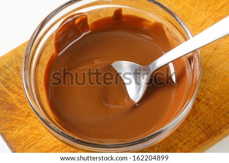 liquid chocolate in a glass bowl on a wooden cutting board