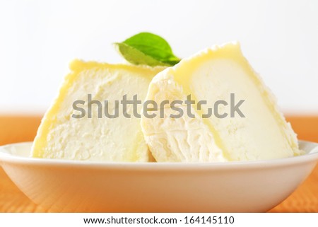 macro detail of goat cheese with a basil leaf