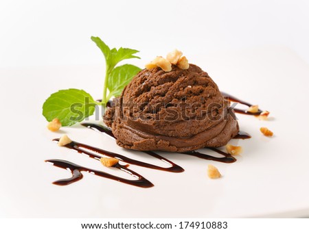 scoop of dark chocolate ice cream decorated with nuts and chocolate sauce