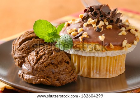 two scoops of chocolate ice cream with vanilla muffin sprinkled with nuts and chocolate flakes