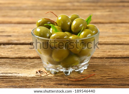 green olives pickled in oil, served in the glass bowl