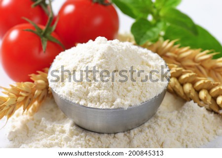 detail of small bowl with flour, wheat ear and fresh tomatoes