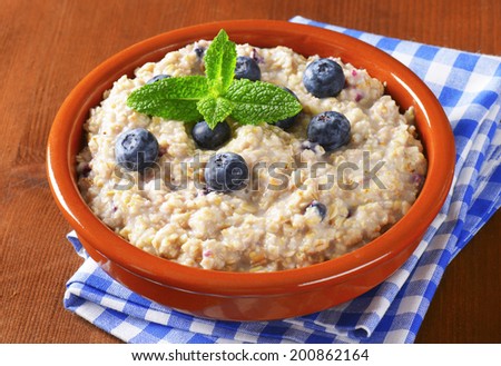 bowl of oatmeal with blueberries in the ceramic bowl with blue patterned linen