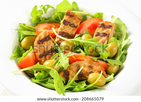 Sliced grilled patty on nest of rocket salad with tomato and olives