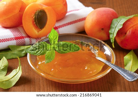 ripe apricots and bowl of apricot jam on wooden table