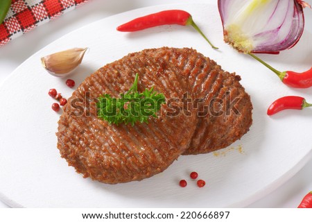 two grilled burgers with chili pepper, garlic and pink pepper