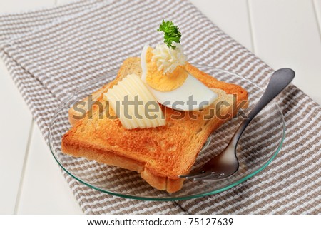 Two pieces of crispy toast, butter and boiled egg
