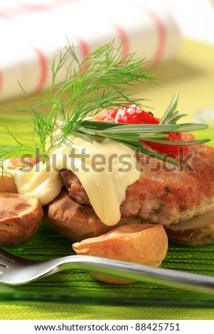 Fried meat patty with roasted potatoes and cheese sauce