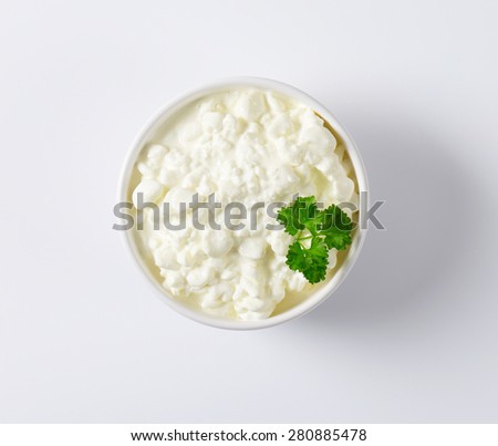 bowl of cottage cheese with fresh parsley on white background