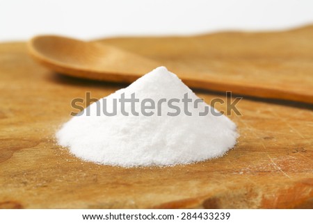 handful of cooking soda and spoon on wooden cutting board