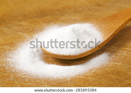 spoon of cooking soda on wooden cutting board