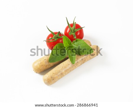 pair of white sausages, fresh basil and cherry tomatoes on white background
