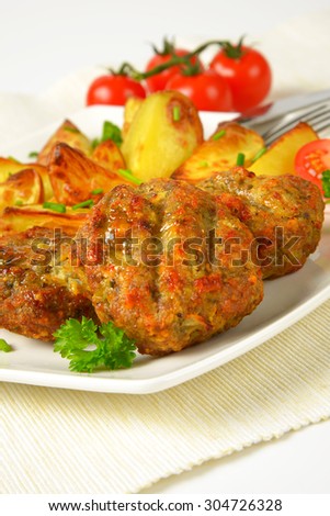 plate of roasted potatoes and fried meatballs on white place mat