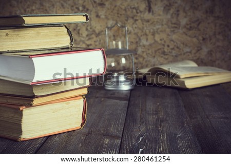 Stack of old books on an old wooden table background.Selective focus.Toned images.