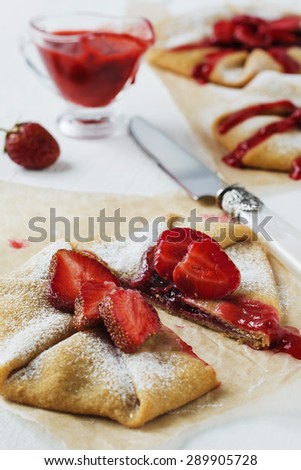 Homemade pie or galette with strawberries sauce and fresh strawberries on white wooden background.Selective focus.