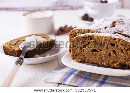 Banana bread with powdered sugar, cream cheese, cinnamon and dates on white wooden background.