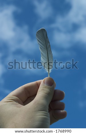 Hand holding feather up to the sky