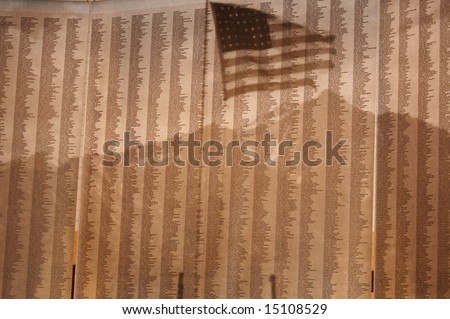 A list of fallen soldiers\' names, with a flag reflected in front of them.