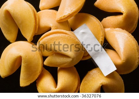 A pile of fortune cookies with a blank fortune laying on top.