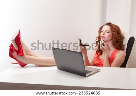 beautiful girl in  pink dress sitting in  office chair behind a white Desk with his feet on  table