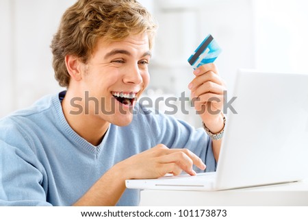Attractive young man using credit card shopping onling at home