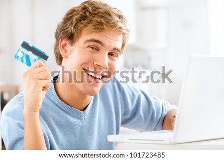 Attractive young man using credit card shopping onling at home u