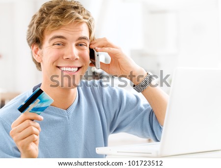 happy young student shopping online using credit card at home