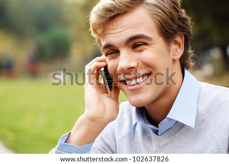 Happy man holding mobile phone outdoors