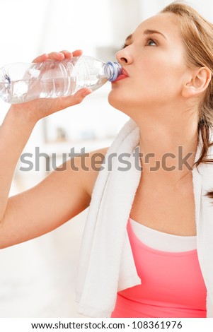 Portrait of attractive young woman drinking water at gym