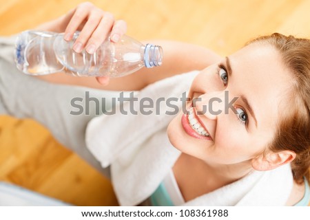 Healthy young sportswoman drinking water at gym