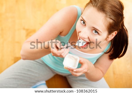 High key Portrait  young caucasian woman eating yogurt at home
