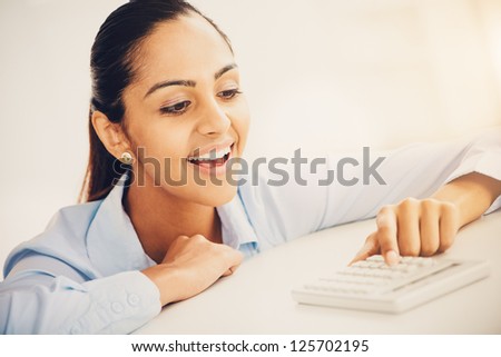 Happy Indian business woman using calculator