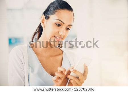 Beautiful Indian woman sending text message mobile phone happy