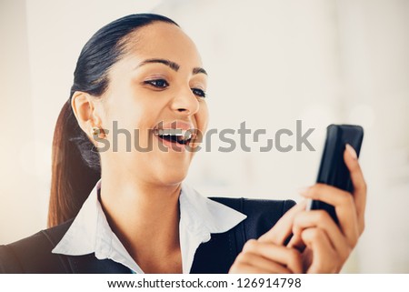 Closeup portrait of beautiful Indian businesswoman sending text message using mobile phone