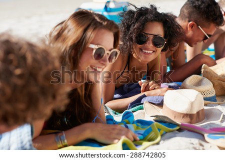 Close up of mixed race group of attractive young people hanging out at the beach faces smiling and enjoying the sunshine