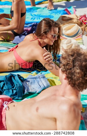 Attractive young woman tanning with her friends at the beach
