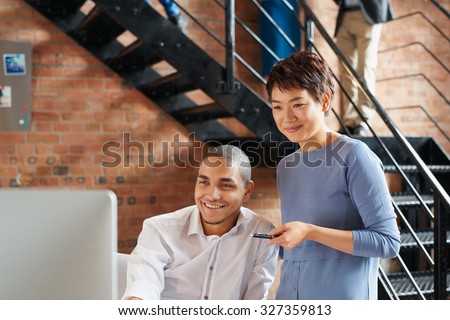 Businessmen and businesswomen working over computer in busy office