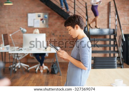 Asian businesswoman using digital tablet technology in trendy office space