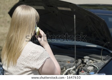 A young lady experiencing car trouble calls for help using her cell phone.