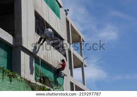 Hua Hin Thailand : 21 Sep 2014 - Unidentified  man is hanging on the rope doing plaster work on a building in Thailand