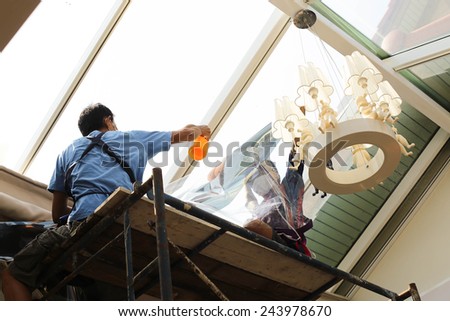unidentified  people wrappers tinting a glass house window with a tinted foil or film using foggy spray