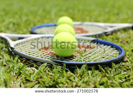Tennis racket with balls on the grass in blur background