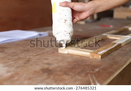 Carpenter putting glue on a piece ofcedar wood in blur background