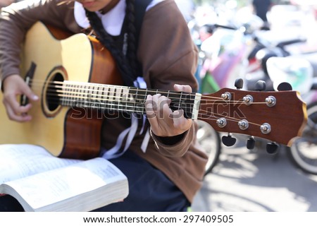 Teenage school girl playing an acoustic guitar with guitar song book